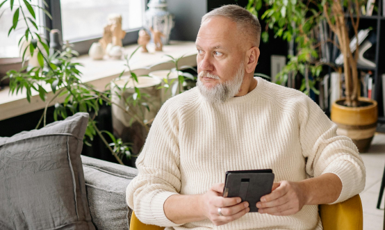 Man on tablet device looking out window
